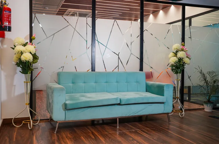 Lounge sofa beside glass partitions at Suits Vaishali Nagar