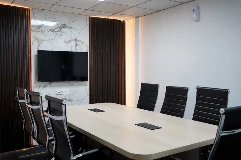 Meeting table and wall-mounted display at Suits Vaishali Nagar